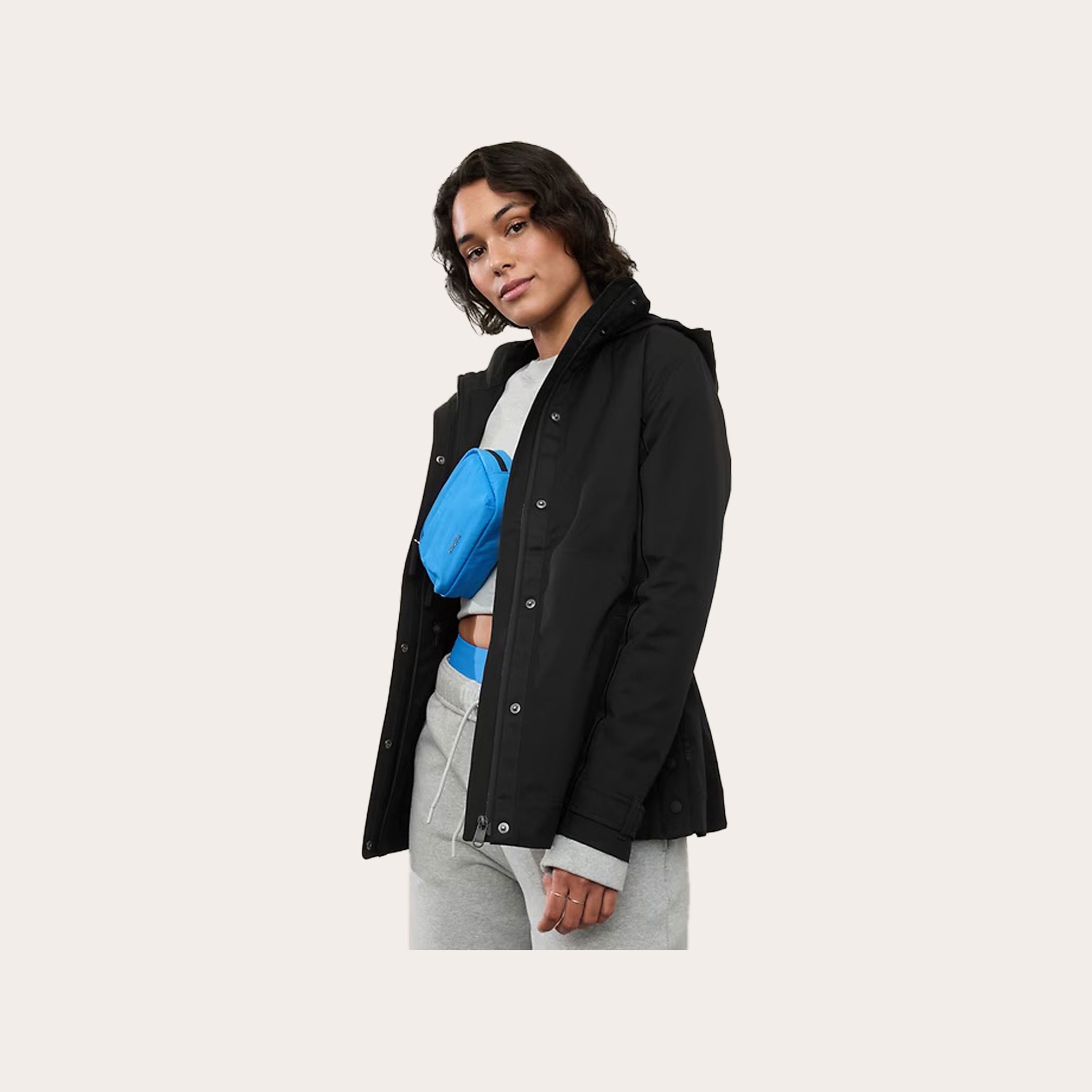 Woman wearing a black rain jacket placed in front of tan background.