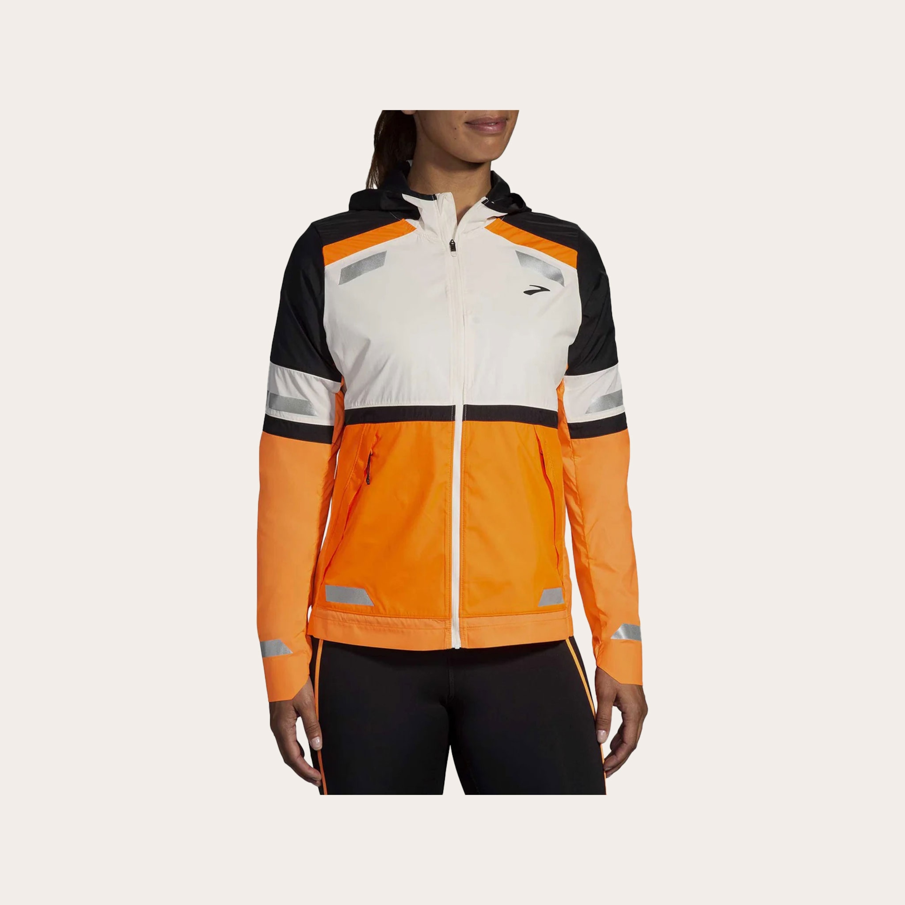 Woman wearing an orange and white rain jacket placed in front of a tan background.