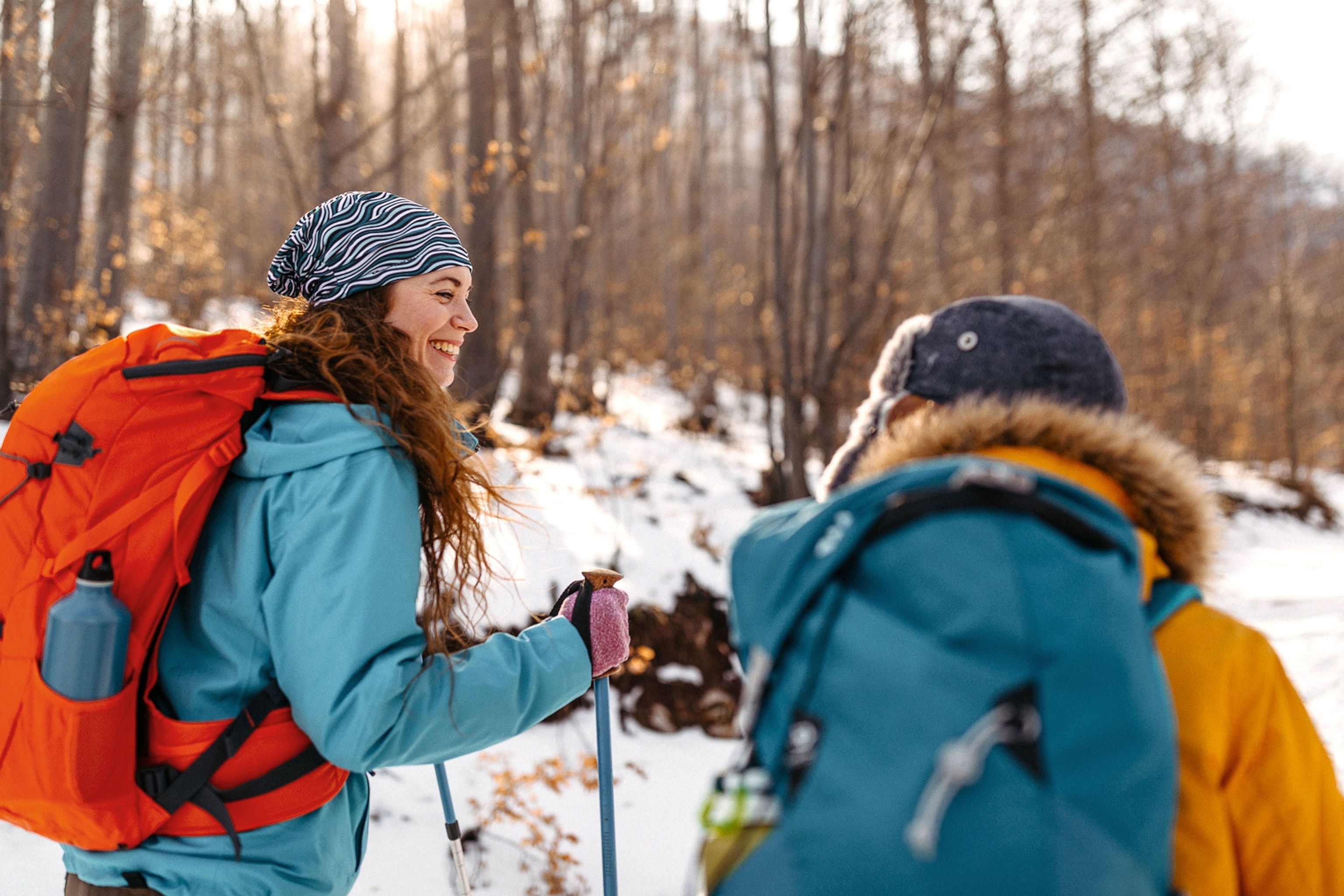 Two people hiking in slow with colorful jackets and backpacks.