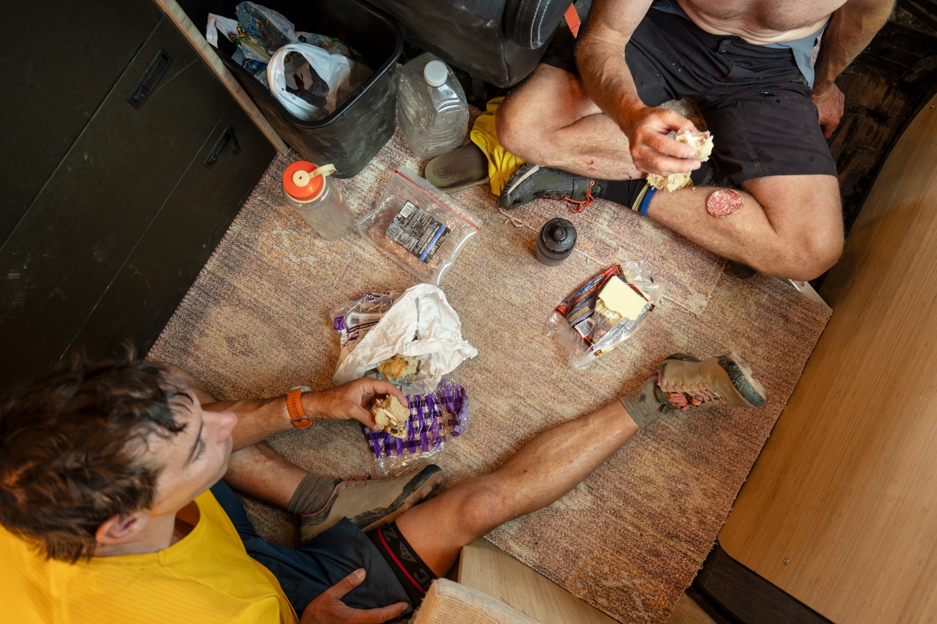 Honnold and Caldwell sitting on the ground sharing a meal