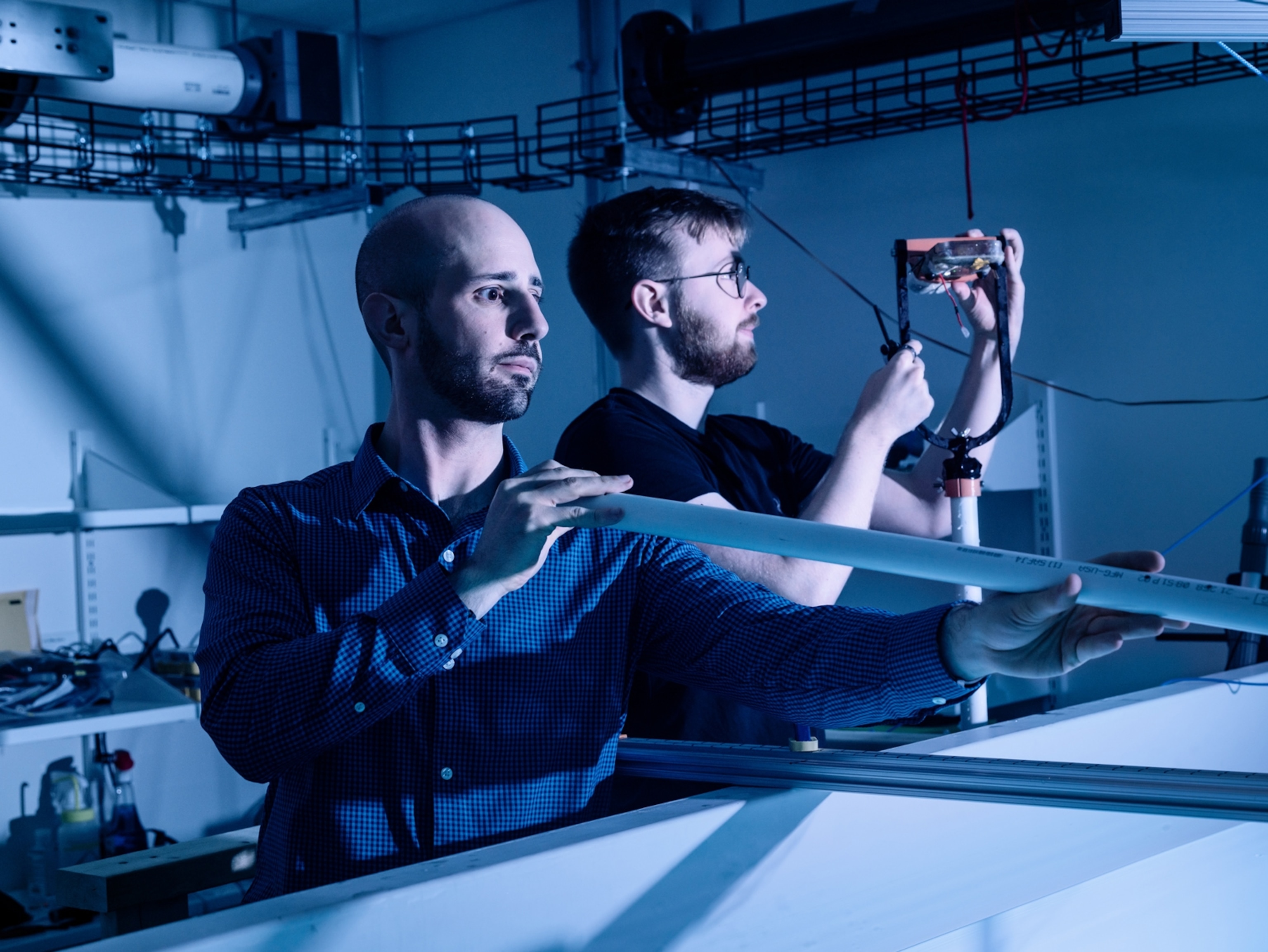 Two men are looking at objects in a lab.