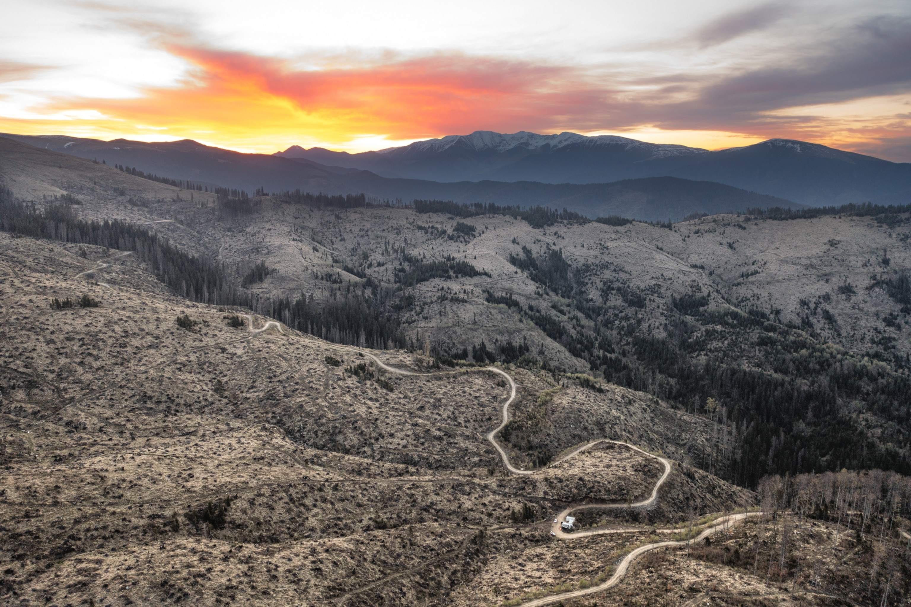 view of eroded land with a dirt path and an orange sky