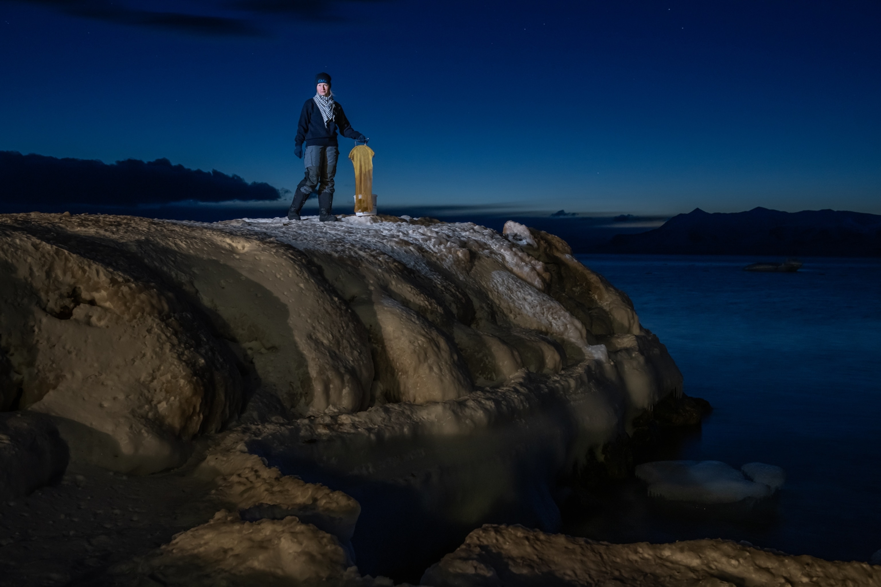 Portrait of Koch standing on the edge of a low cliff with a yellow net and bucket.